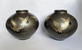 Two black vases with gold bird designs on a white background