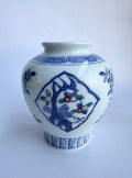 White ceramic vase with blue and green floral patterns on a white background
