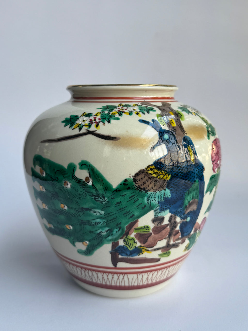 Ceramic vase with peacock design on a white background