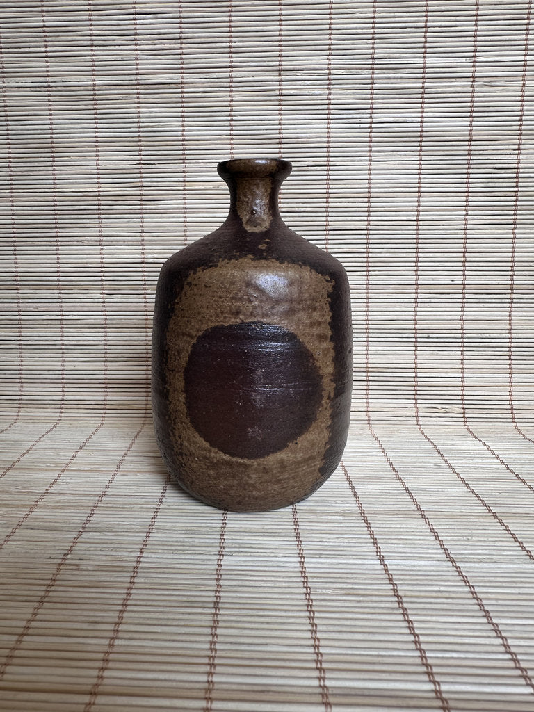 Brown ceramic bottle on a woven mat background