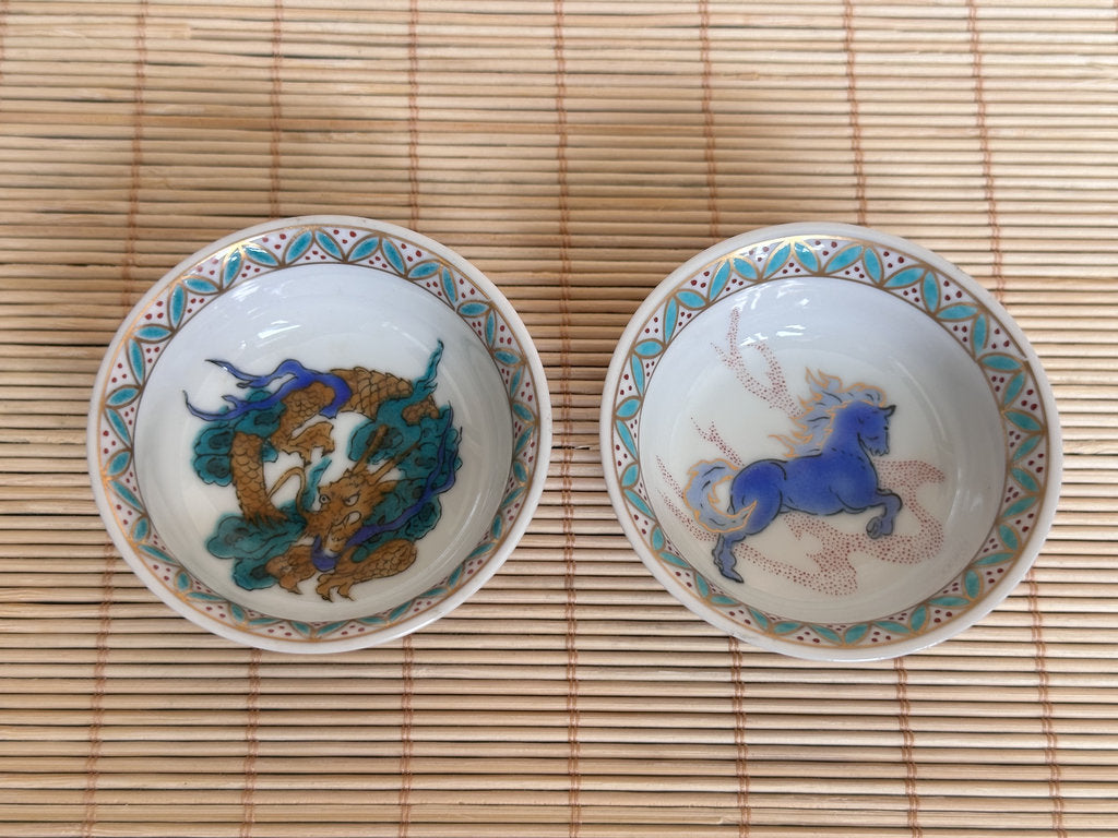 Two ceramic bowls with animal designs on a bamboo mat