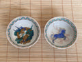 Two ceramic bowls with animal designs on a bamboo mat