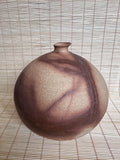 Ceramic vase with a textured surface on a woven mat