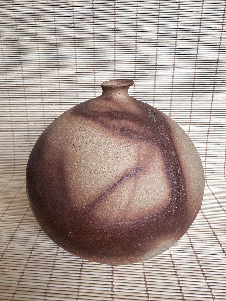 Ceramic vase with a textured surface on a woven mat