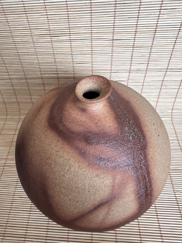 Ceramic vase with a textured surface on a woven mat