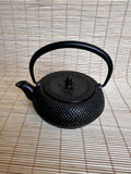 Black textured teapot on a woven mat