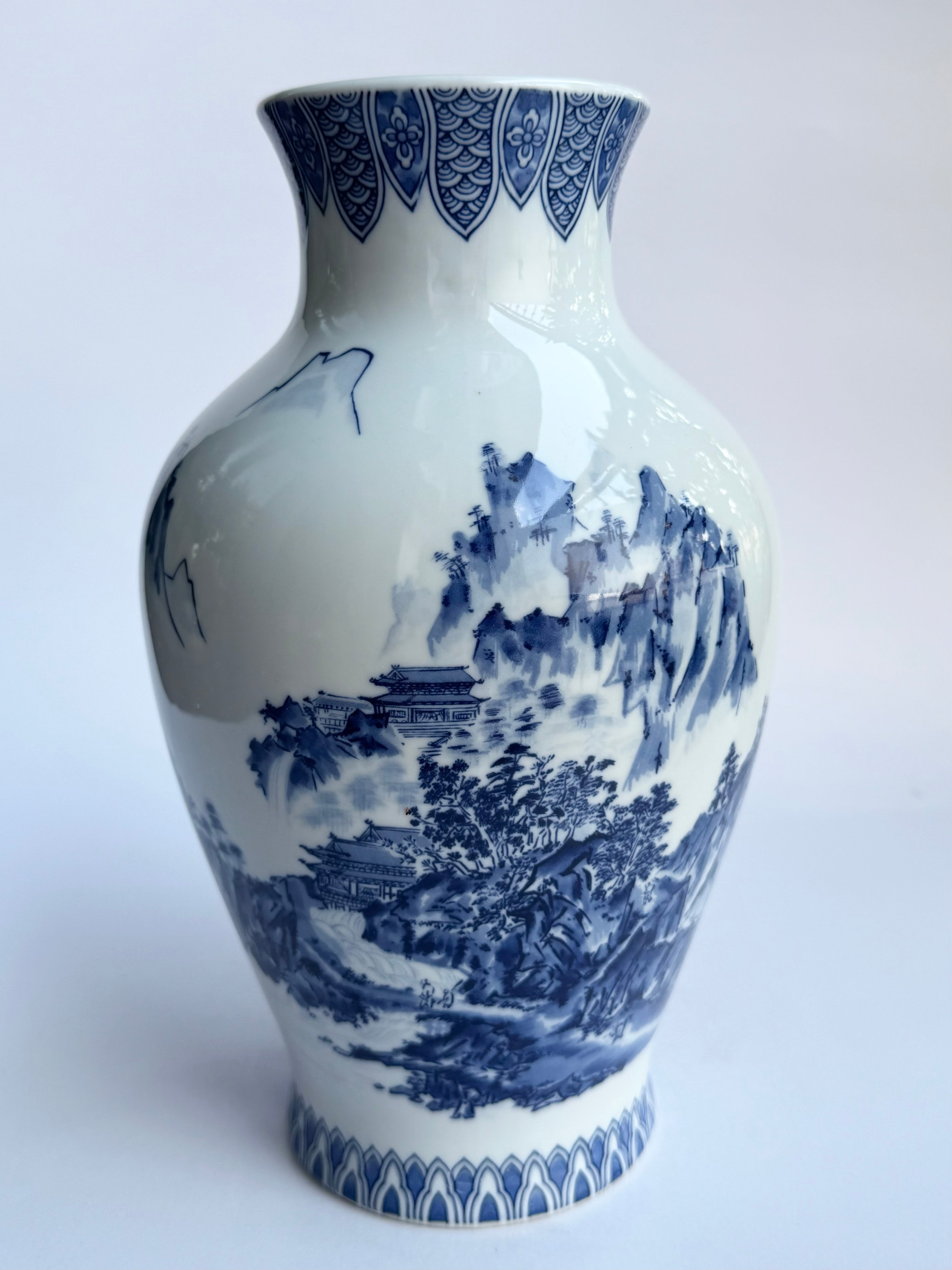 Blue and white ceramic vase with intricate patterns on a white background