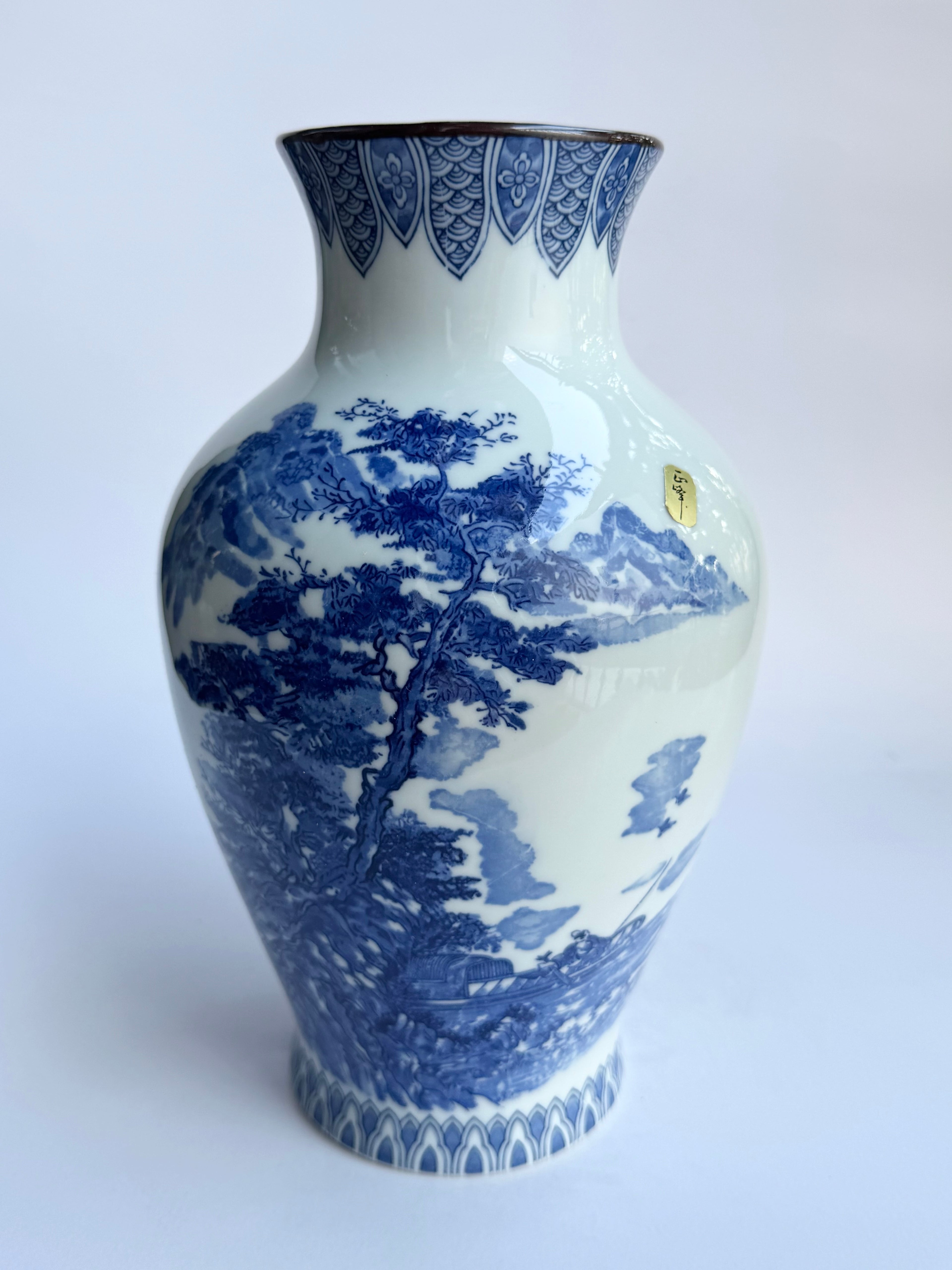 Blue and white ceramic vase with landscape design on a white background