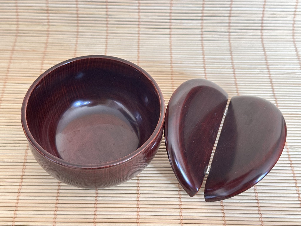 Wooden bowl and lid on a woven mat