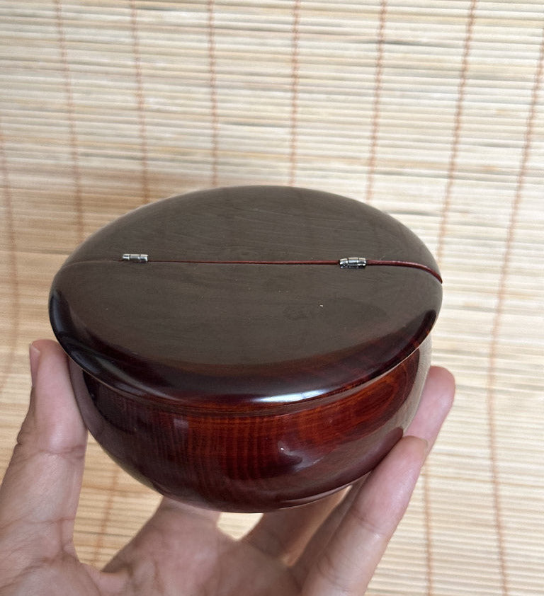 Hand holding a wooden bowl with a bamboo mat background