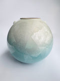 Round ceramic vase with textured surface on a white background