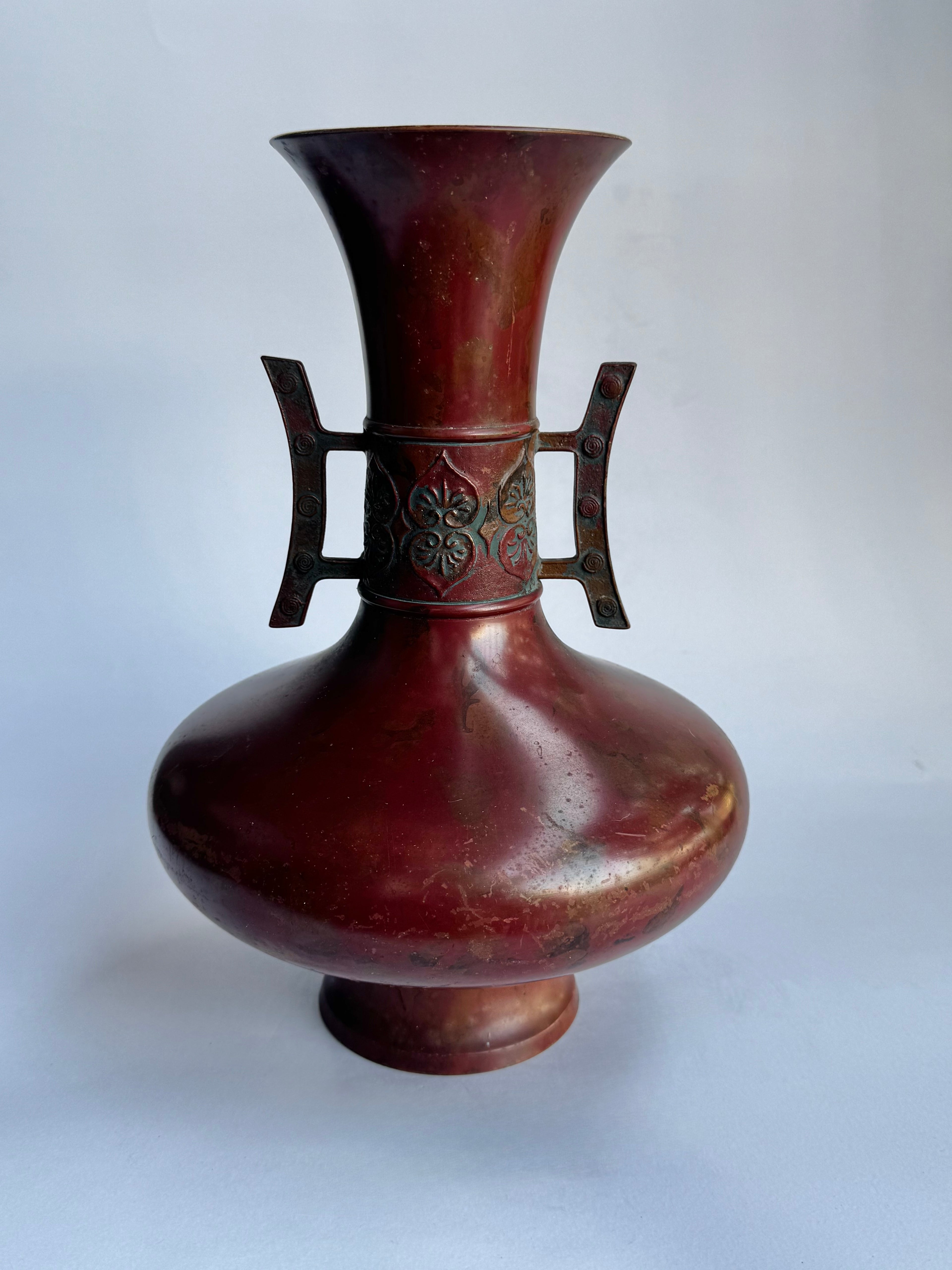 Bronze vase with decorative handles on a white background