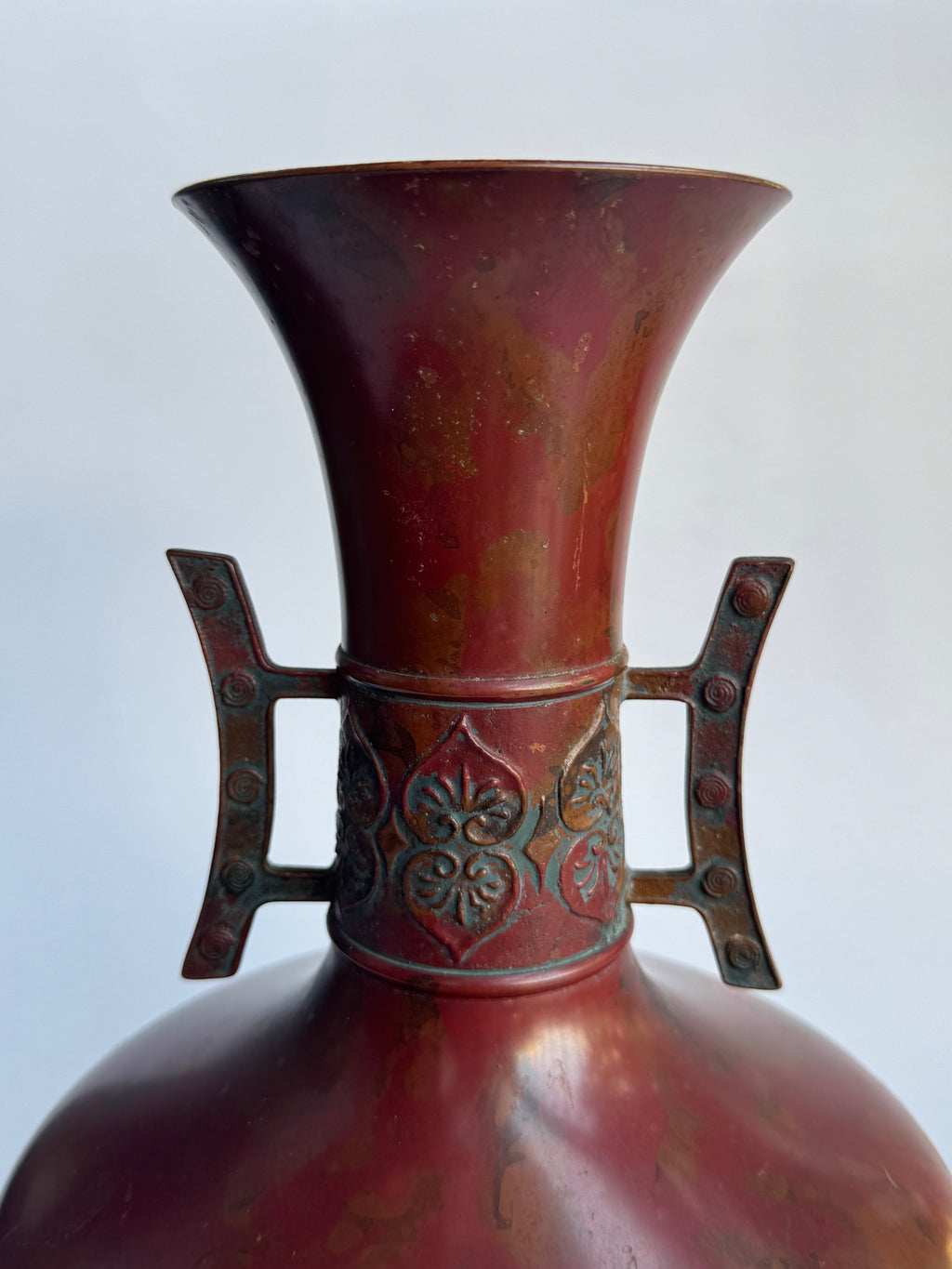 Close-up of a red metal horn with decorative elements on a white background