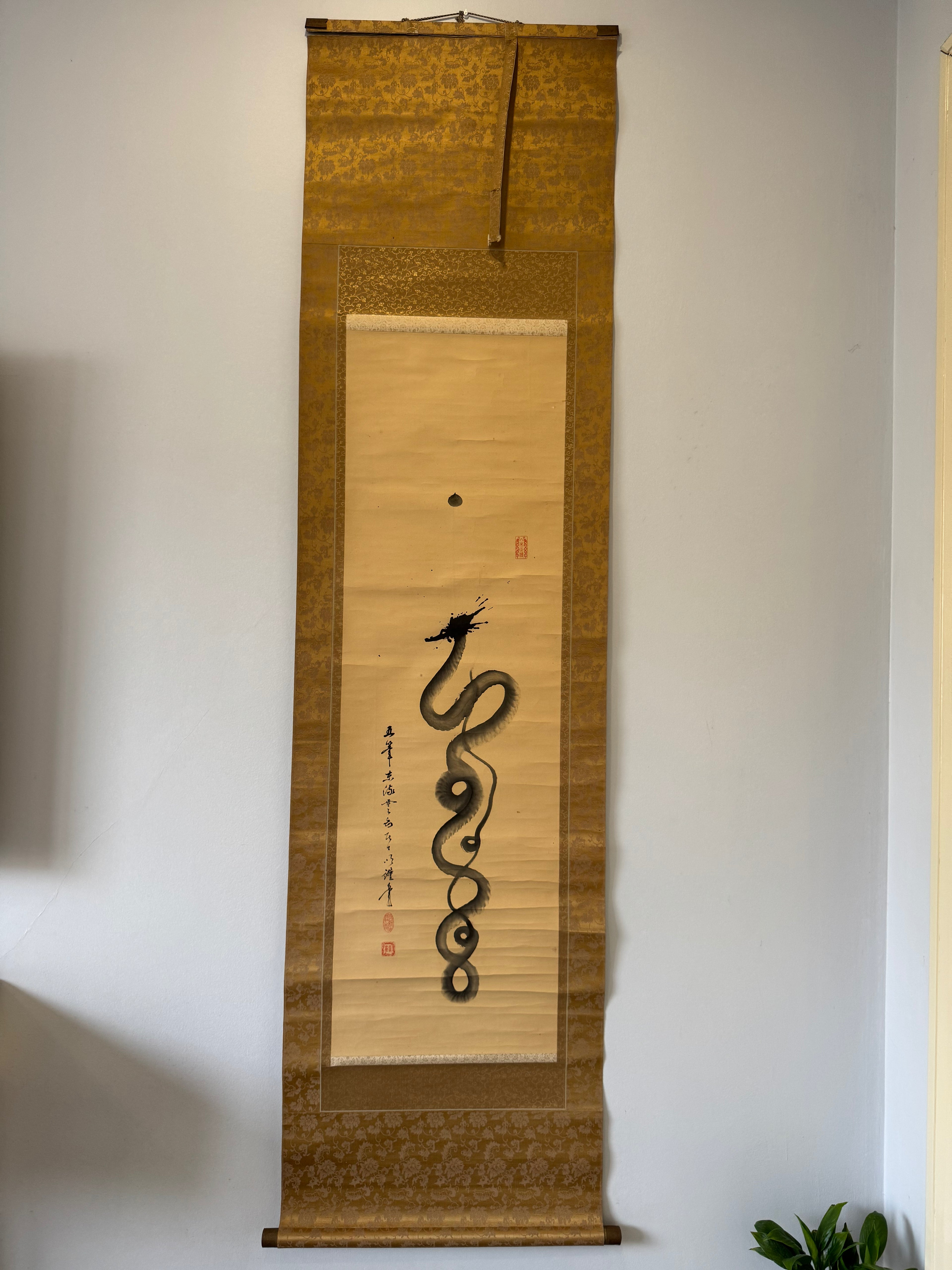 Traditional Japanese scroll with a dragon design on a plain wall.