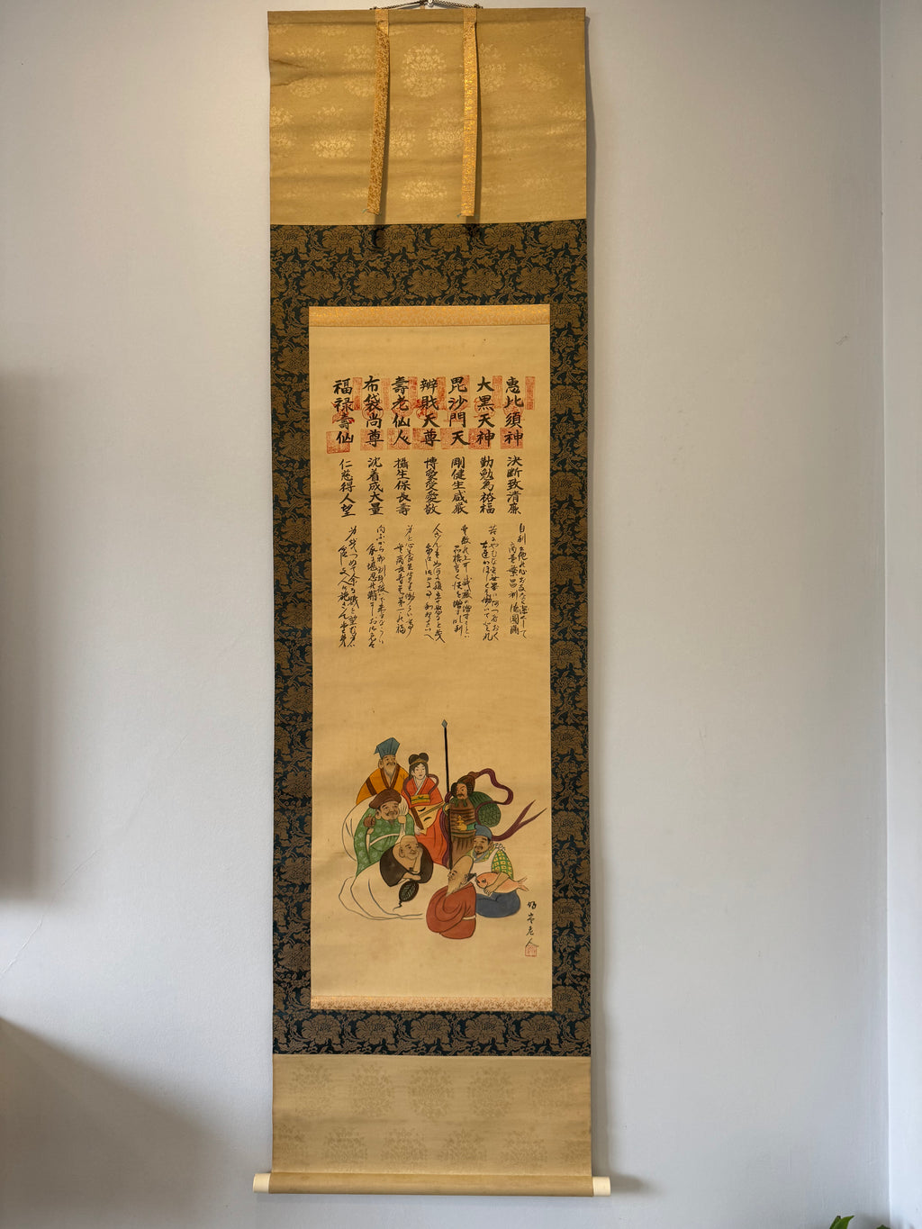 Traditional scroll with artistic depiction and calligraphy on a plain wall