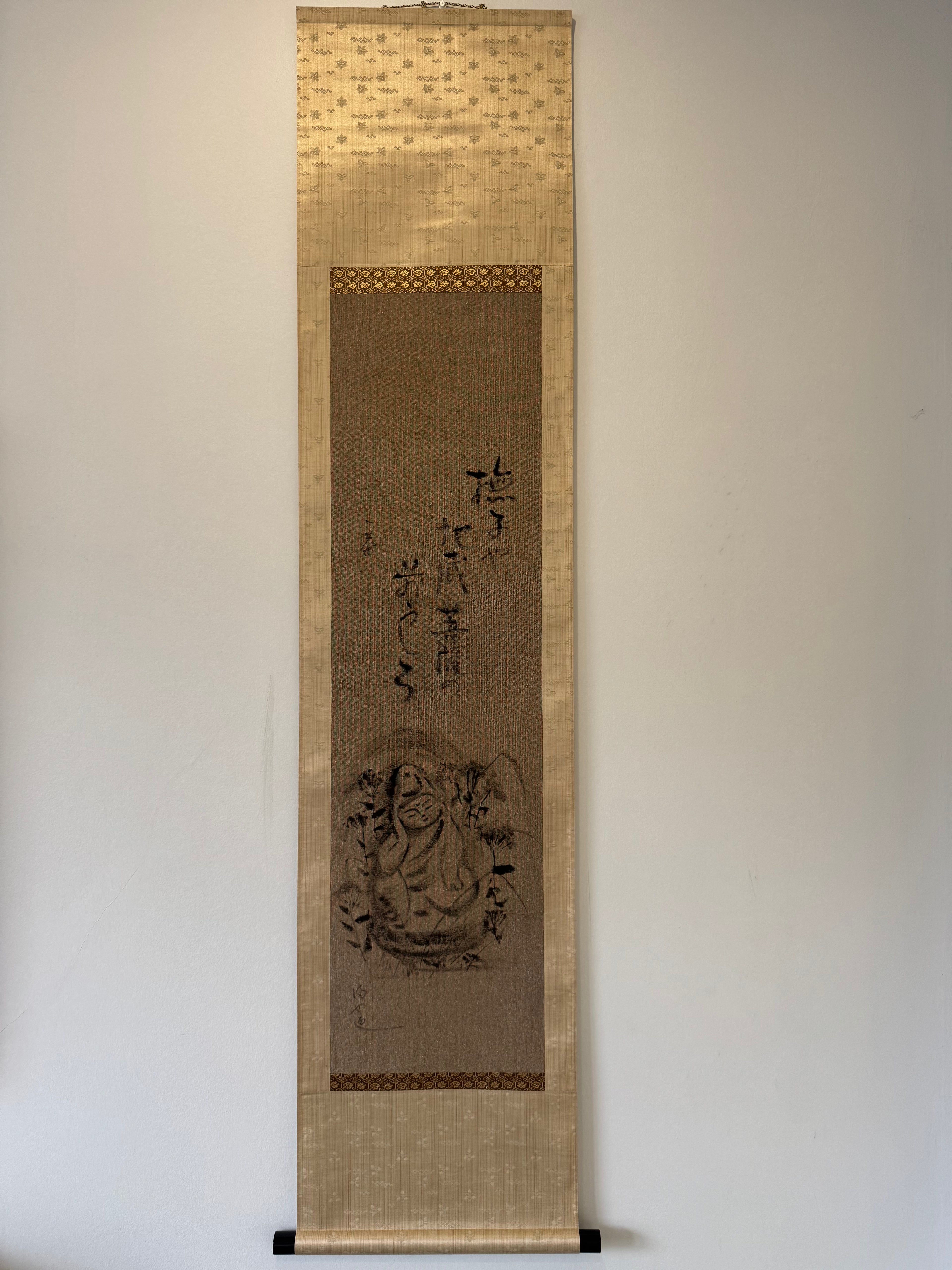 Traditional Chinese scroll with calligraphy and artwork on a plain wall