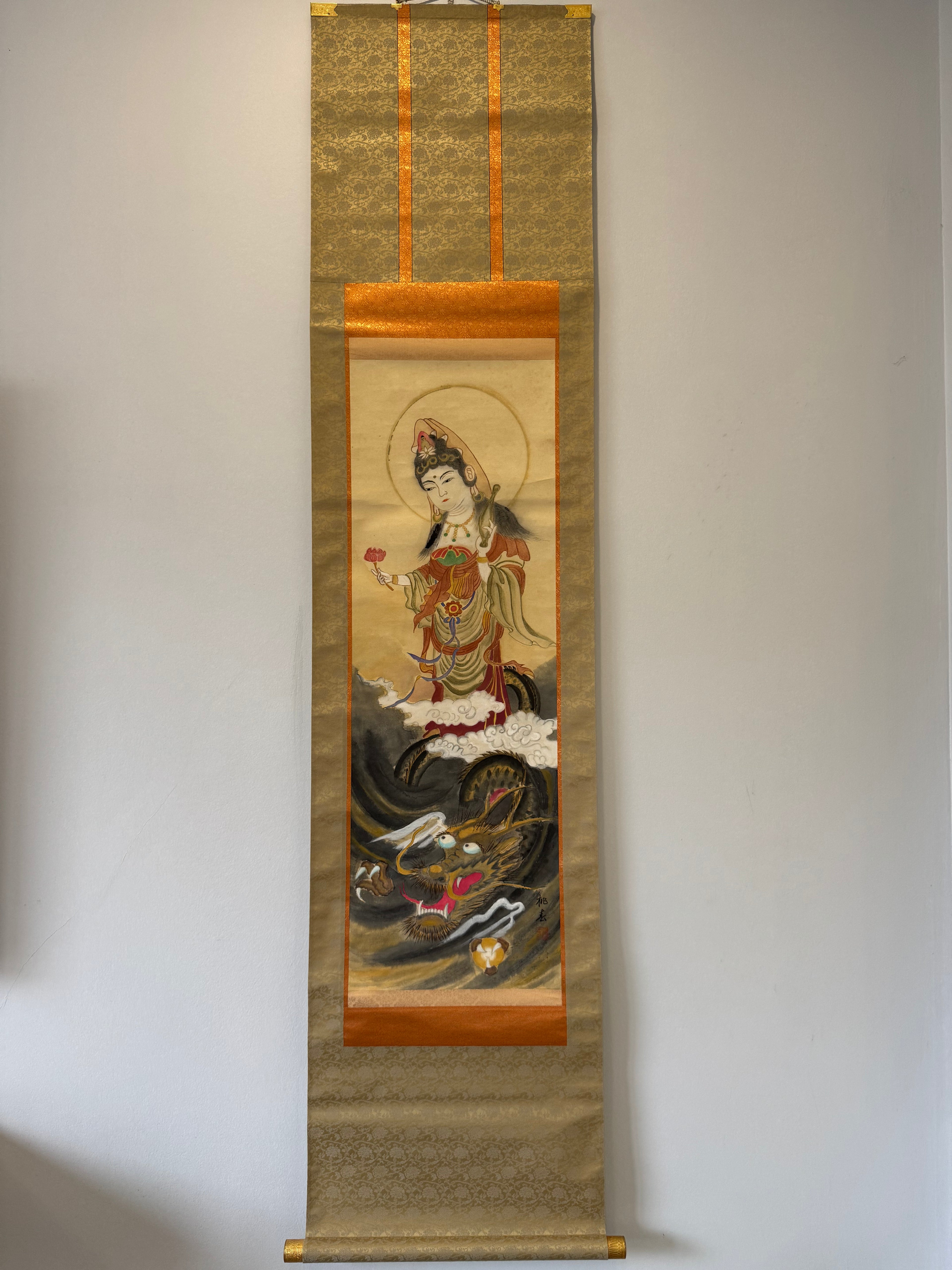 Traditional scroll with a depiction of a figure and dragon on a gold background