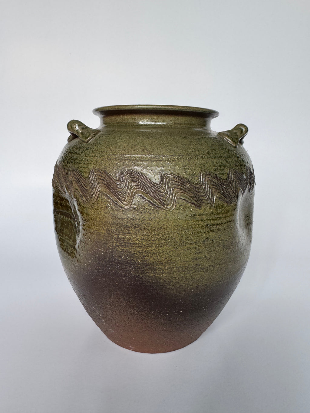 Ceramic jar with wavy pattern on a white background