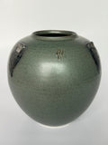 Green ceramic vase with decorative elements on a white background