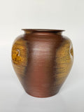Brown ceramic vase with textured surface on a white background