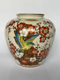 Ceramic vase with floral and bird design on a white background