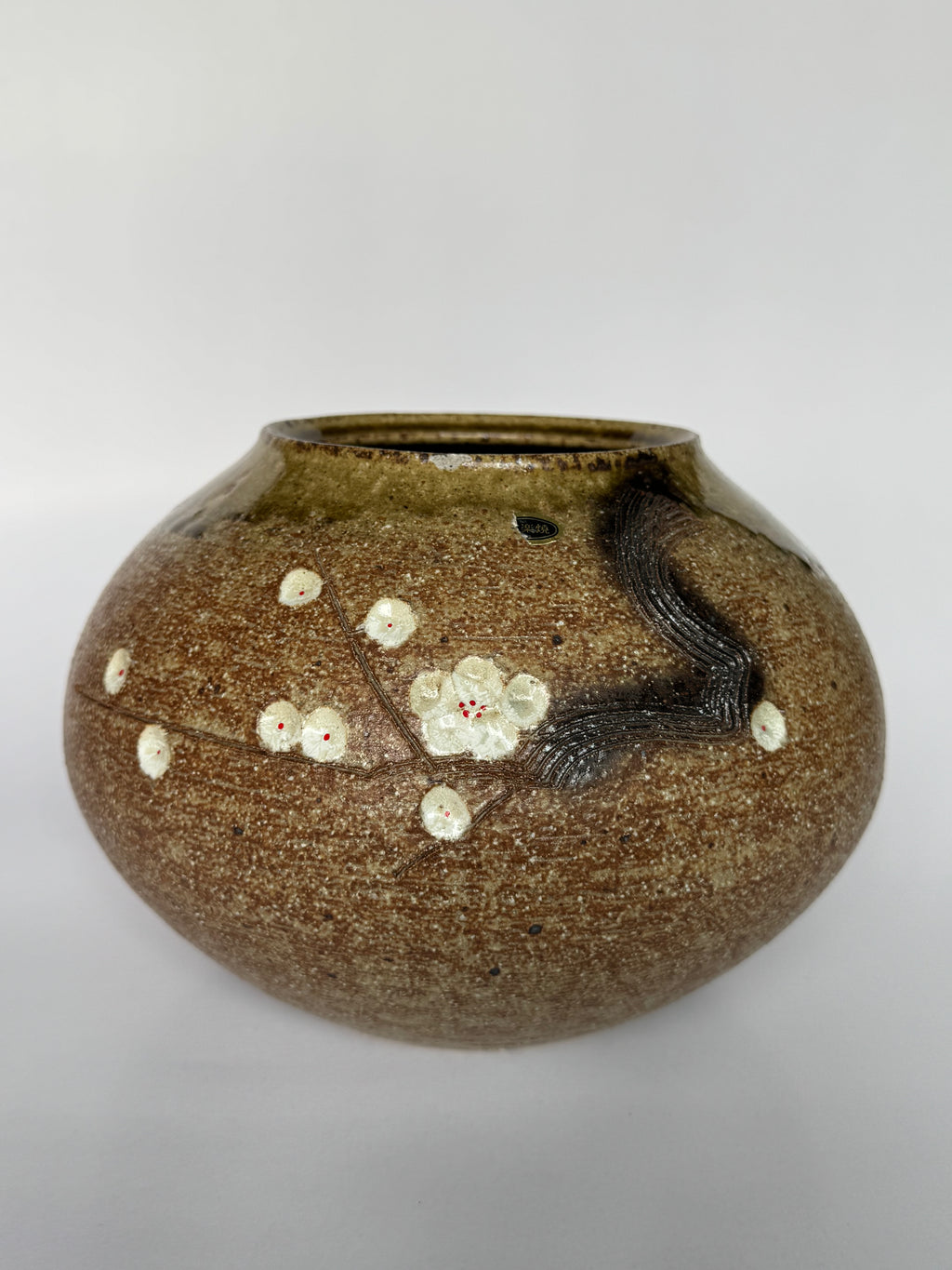 Brown ceramic vase with floral design on a white background