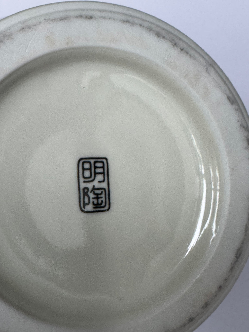 Close-up of a ceramic dish with a signature on a white background