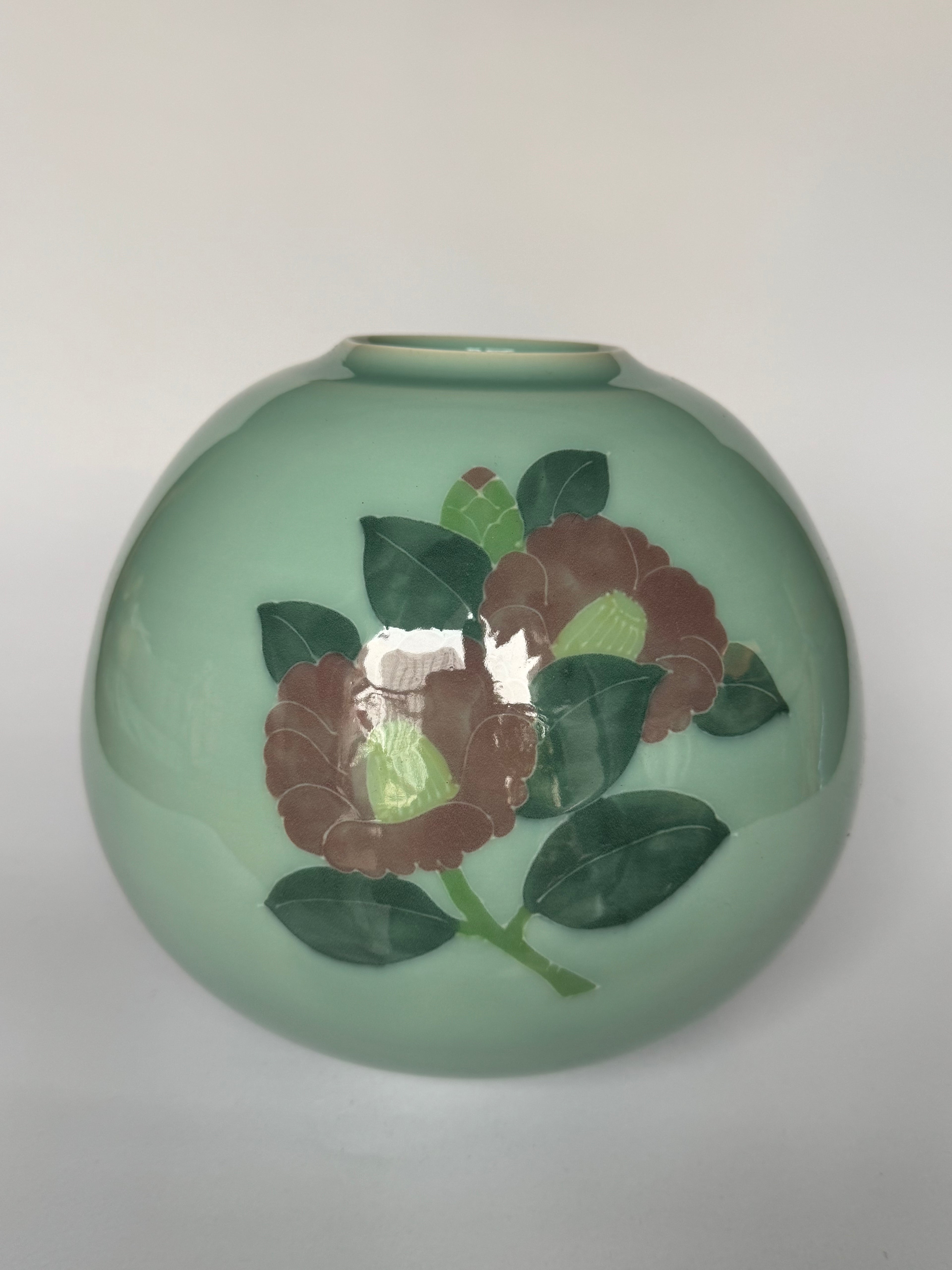 Green ceramic vase with floral design on a white background