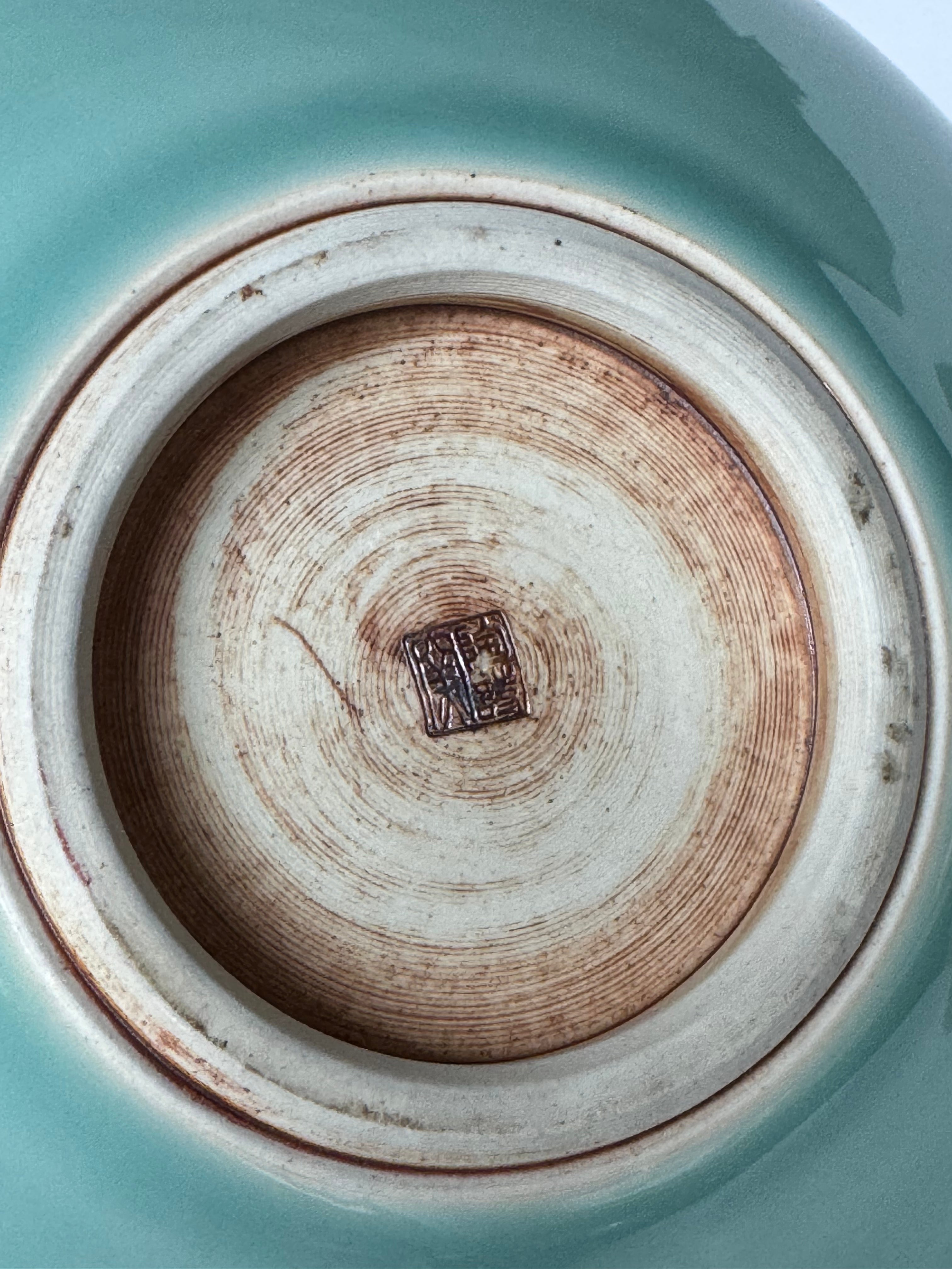 Close-up of a ceramic plate with a visible brand logo on a teal background