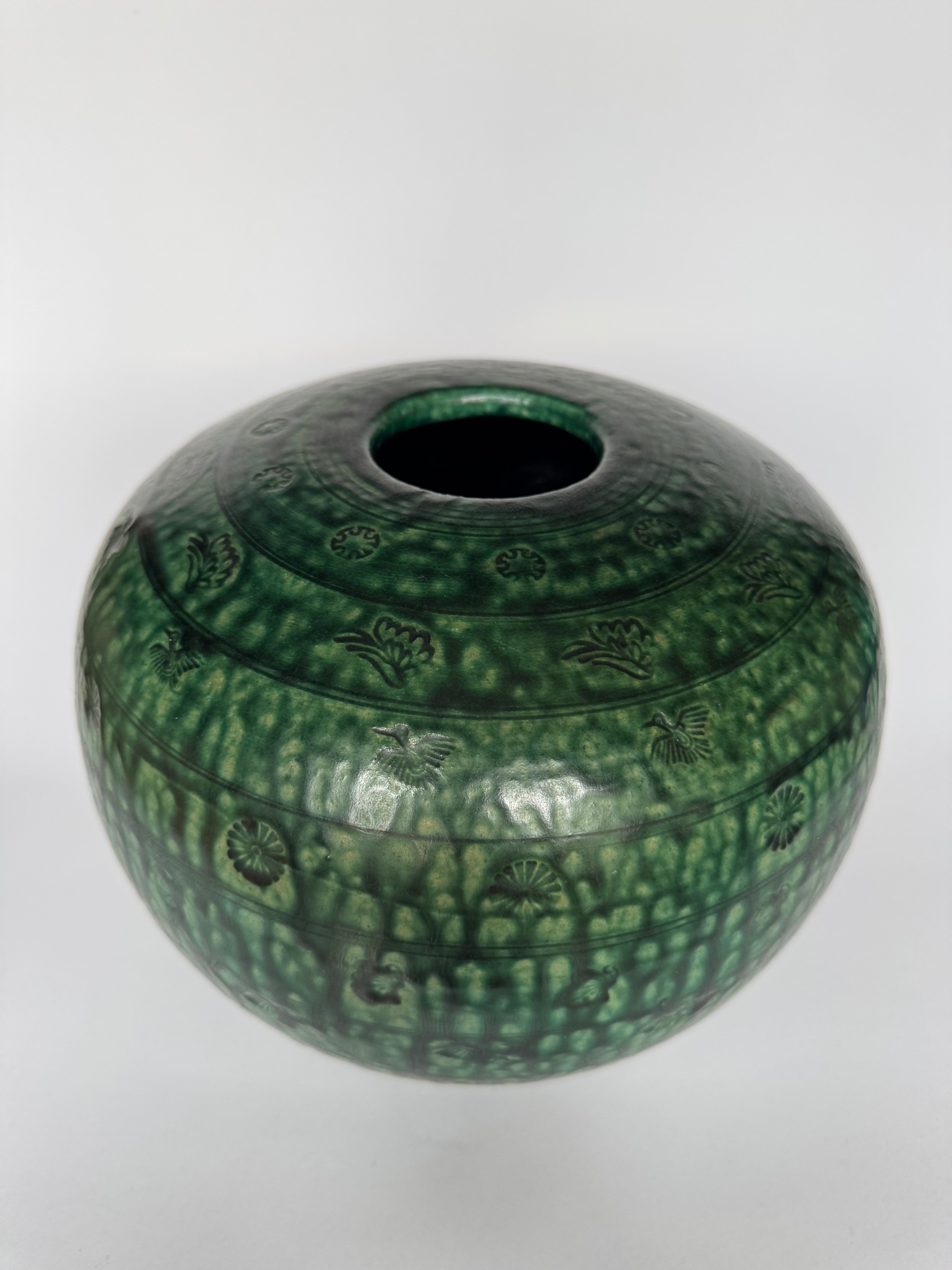 Green ceramic vase with textured pattern on a white background