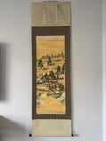 Traditional Japanese landscape painting in a vertical scroll on a plain wall.