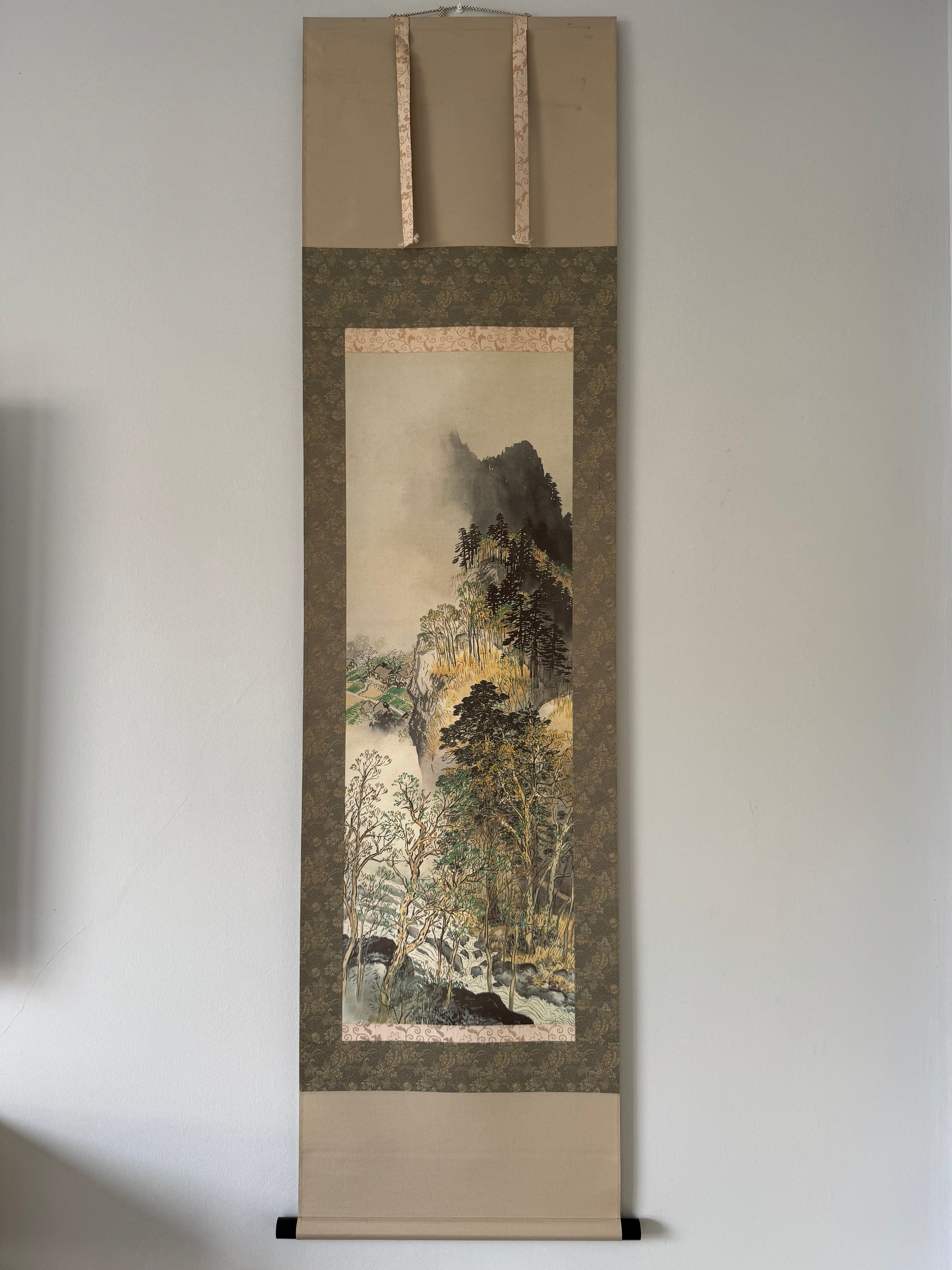 Traditional Japanese landscape scroll art on a plain wall