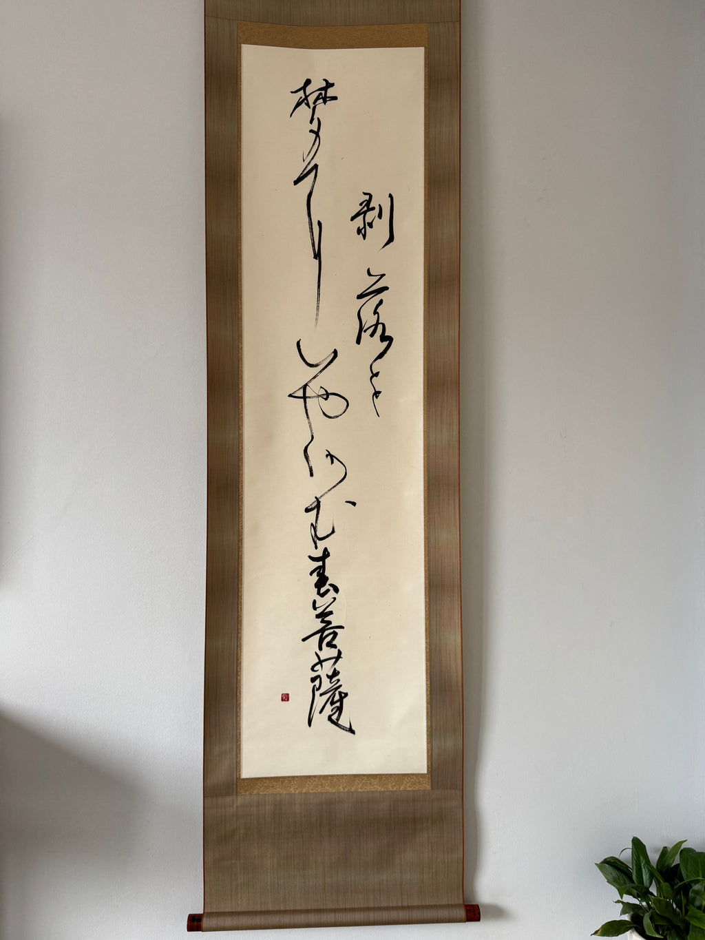 Vertical scroll with calligraphy on a plain wall