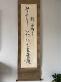 Vertical scroll with calligraphy on a plain wall