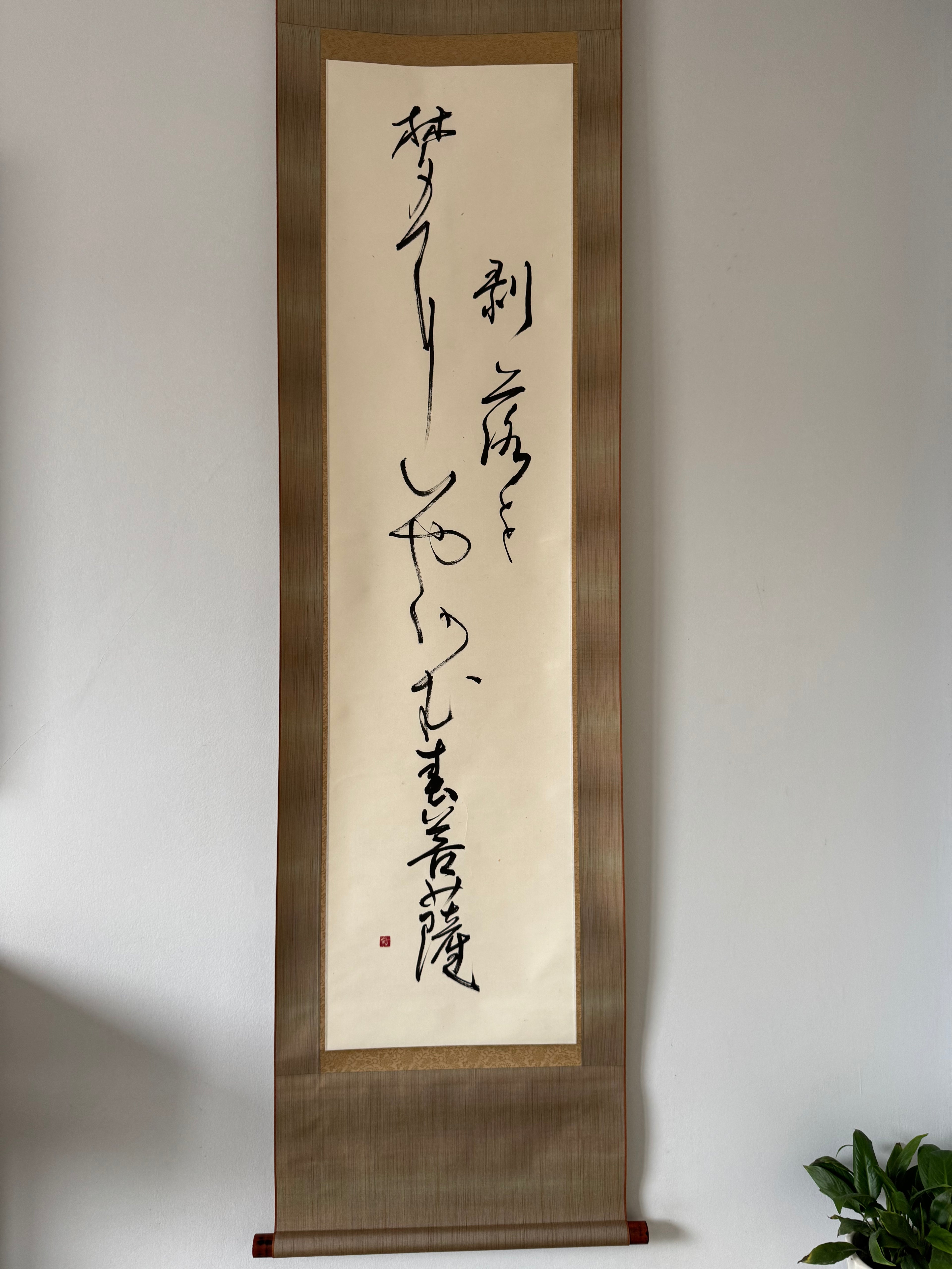 Vertical scroll with calligraphy on a plain wall