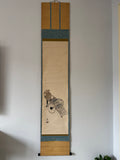 Traditional Japanese scroll with artwork on a plain wall