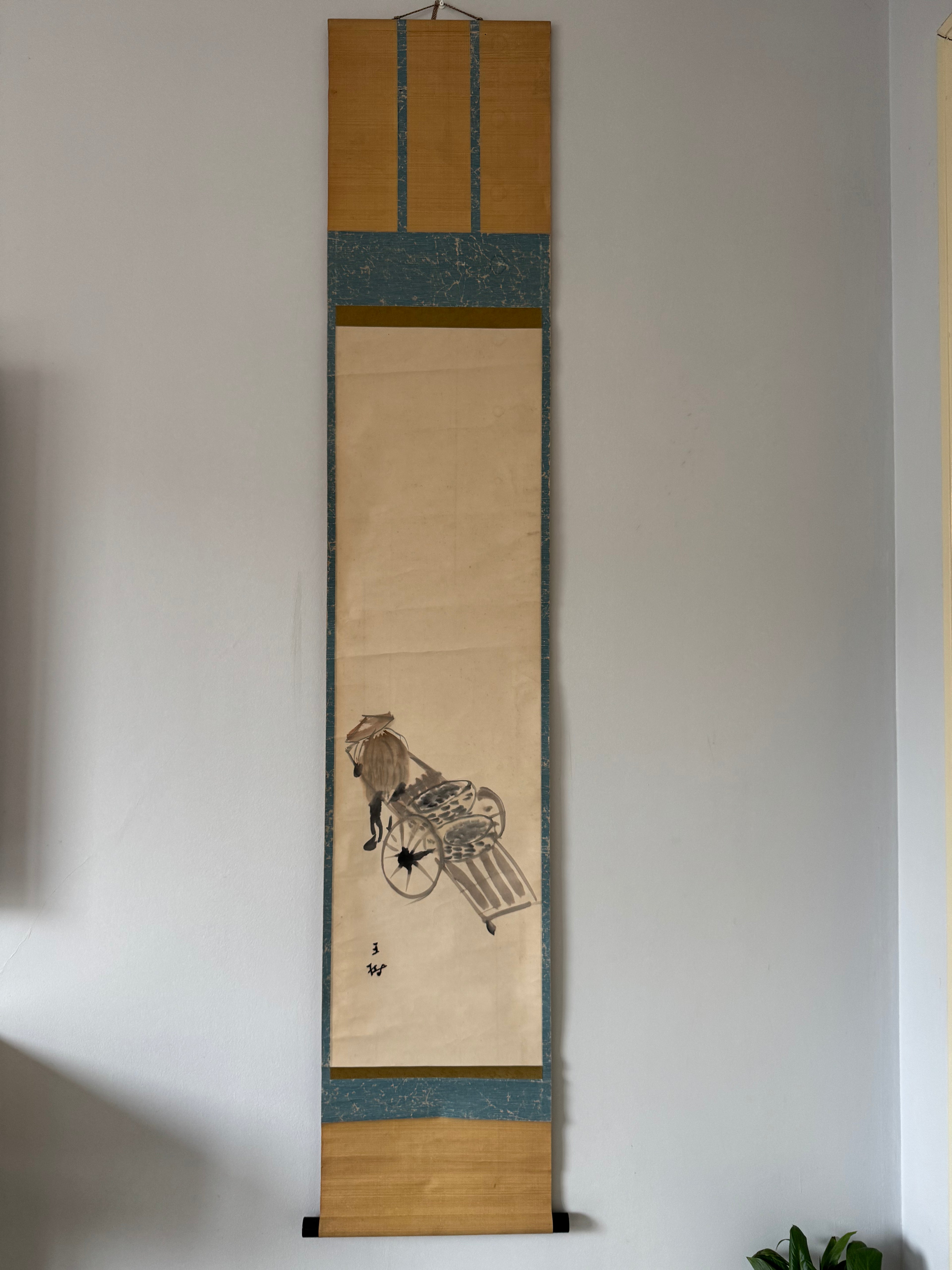 Traditional Japanese scroll with artwork on a plain wall
