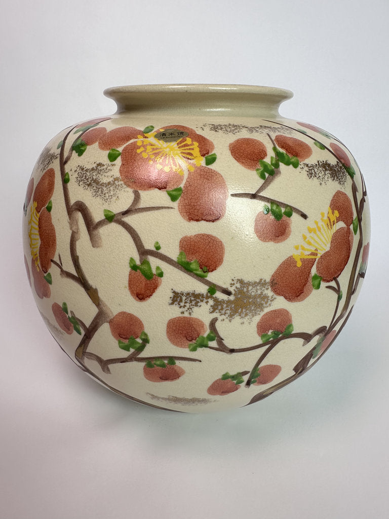 A round ceramic vase with a flared rim, decorated with a hand-painted floral pattern of pink blossoms, green leaves, and yellow centers on a cream background.