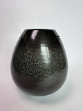 A glossy black ceramic vase with a fine silver speckled glaze, featuring two small metal loop handles on the sides, set against a plain light gray background.