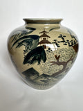 A ceramic garden vase with a rounded body and flared rim, decorated with a hand-painted Japanese landscape scene featuring a pagoda, trees, and mountains in dark green and brown glazes over a warm beige background.