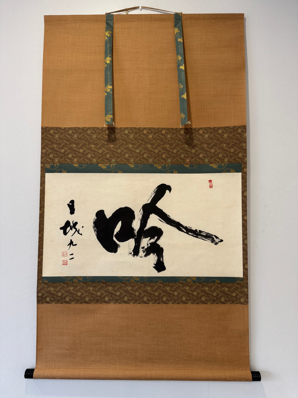 Traditional Japanese calligraphy scroll on a decorative frame with gold accents.