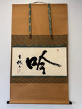Traditional Japanese calligraphy scroll on a decorative frame with gold accents.