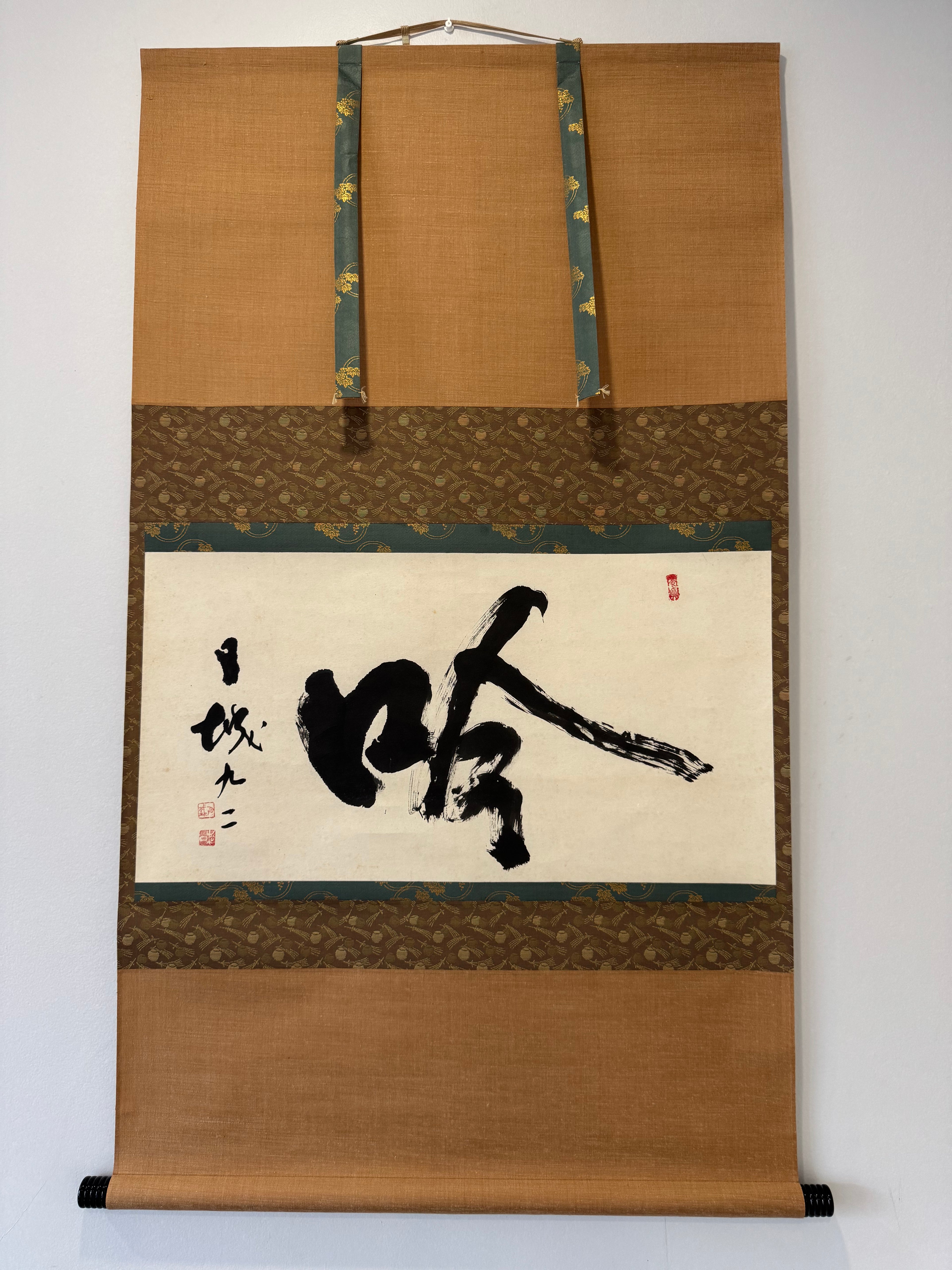 Traditional Japanese calligraphy scroll on a decorative frame with gold accents.