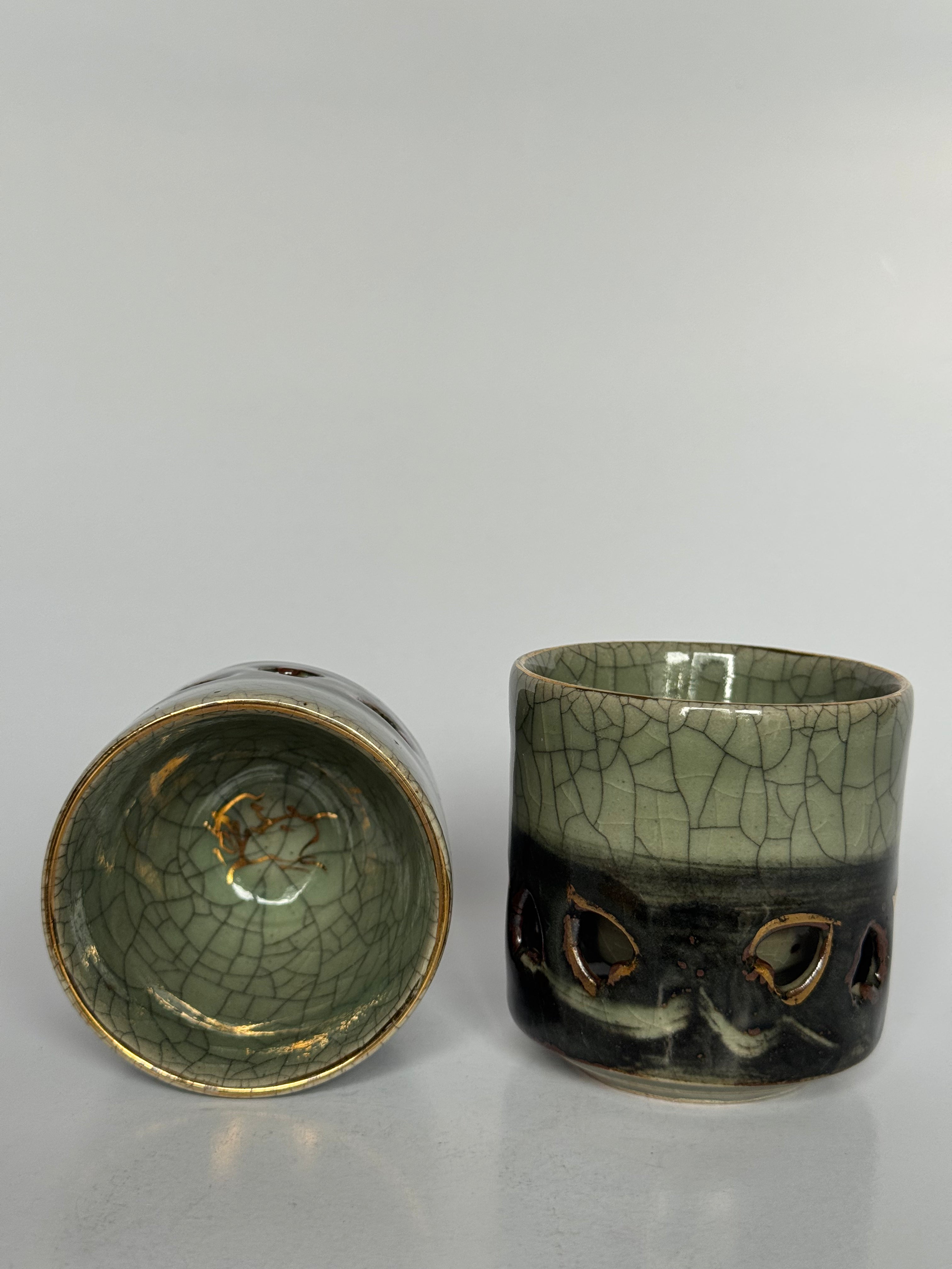 Two ceramic cups with textured surfaces on a gray background