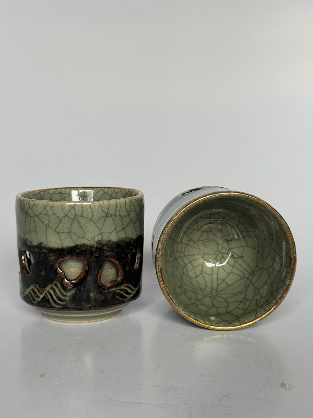 Two ceramic cups with cracked glaze design on a gray background