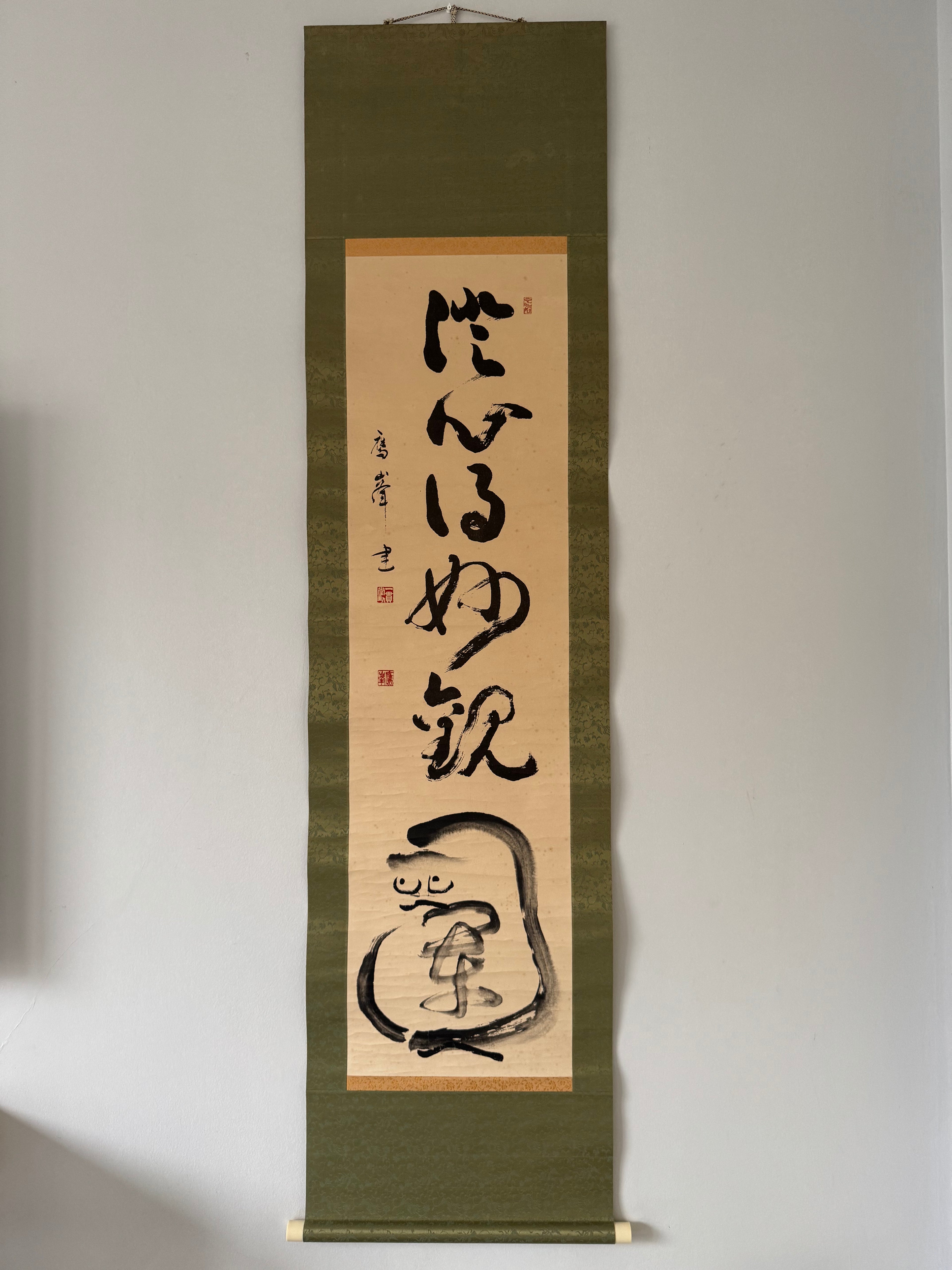 Vertical scroll with calligraphy on a beige background, framed in green.