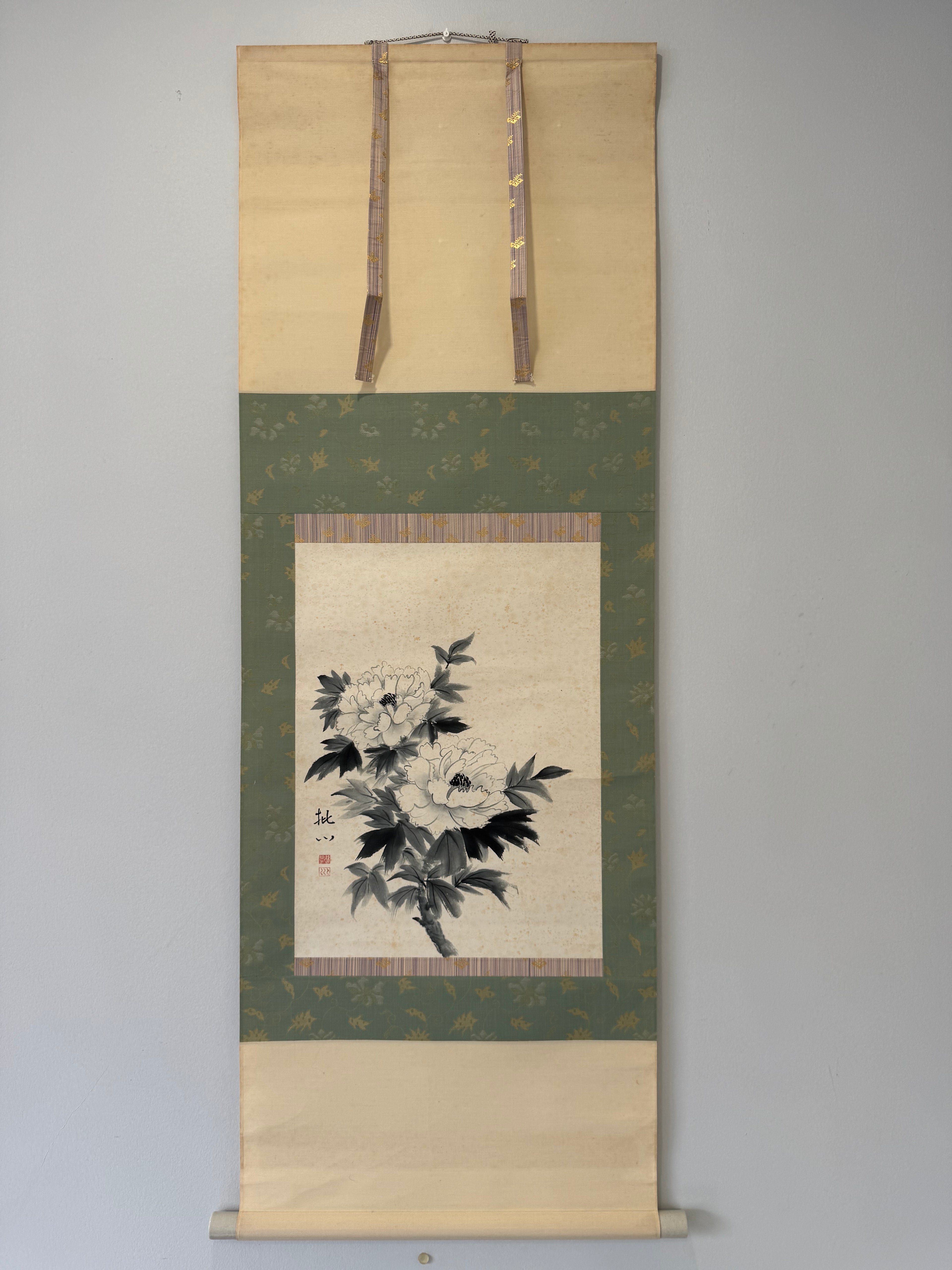 Floral artwork on a green and beige scroll against a gray background