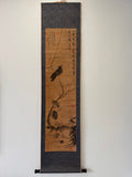 Traditional japanese scroll with ink painting of a bird on a branch against a plain background