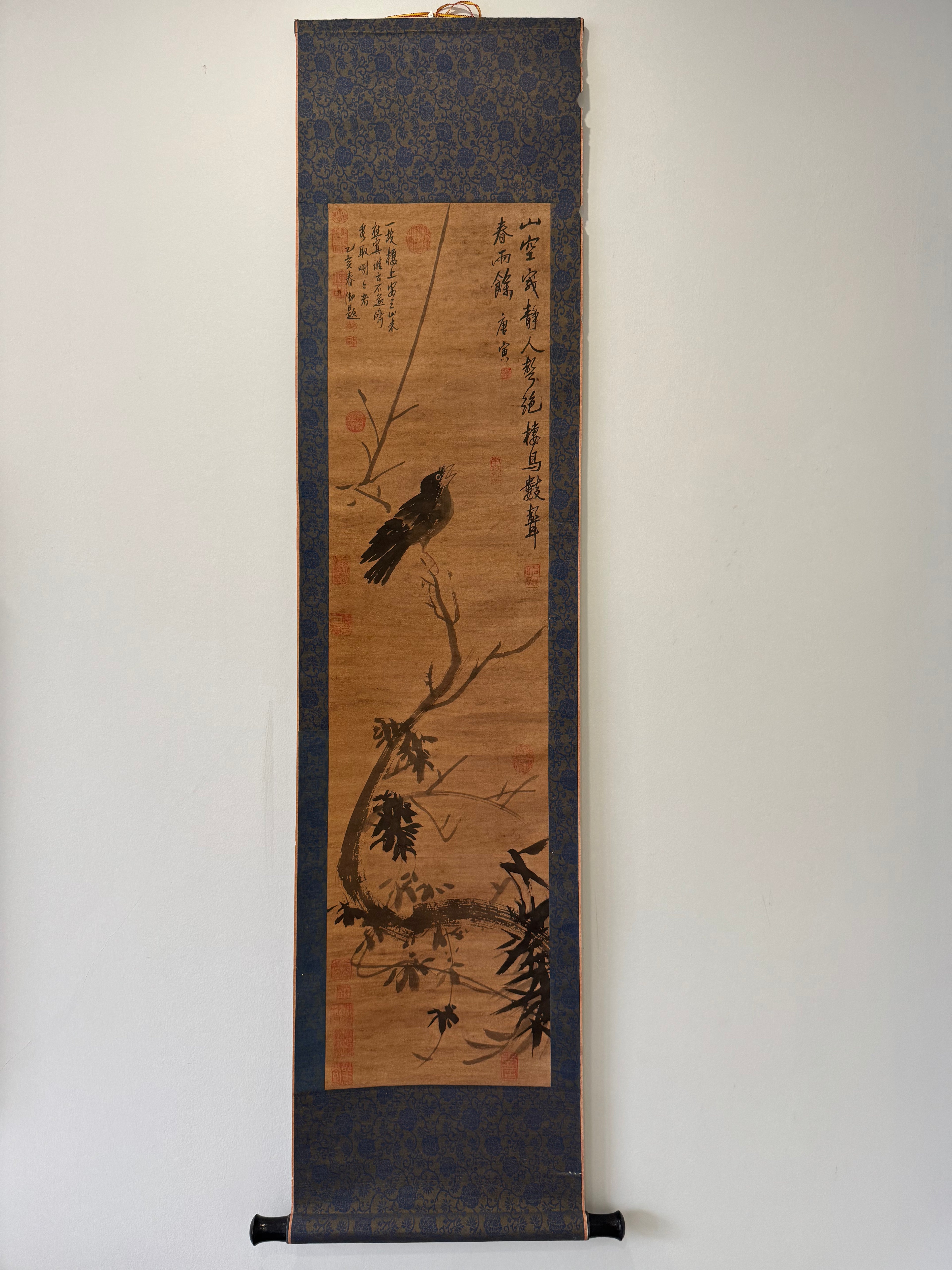 Traditional japanese scroll with ink painting of a bird on a branch against a plain background