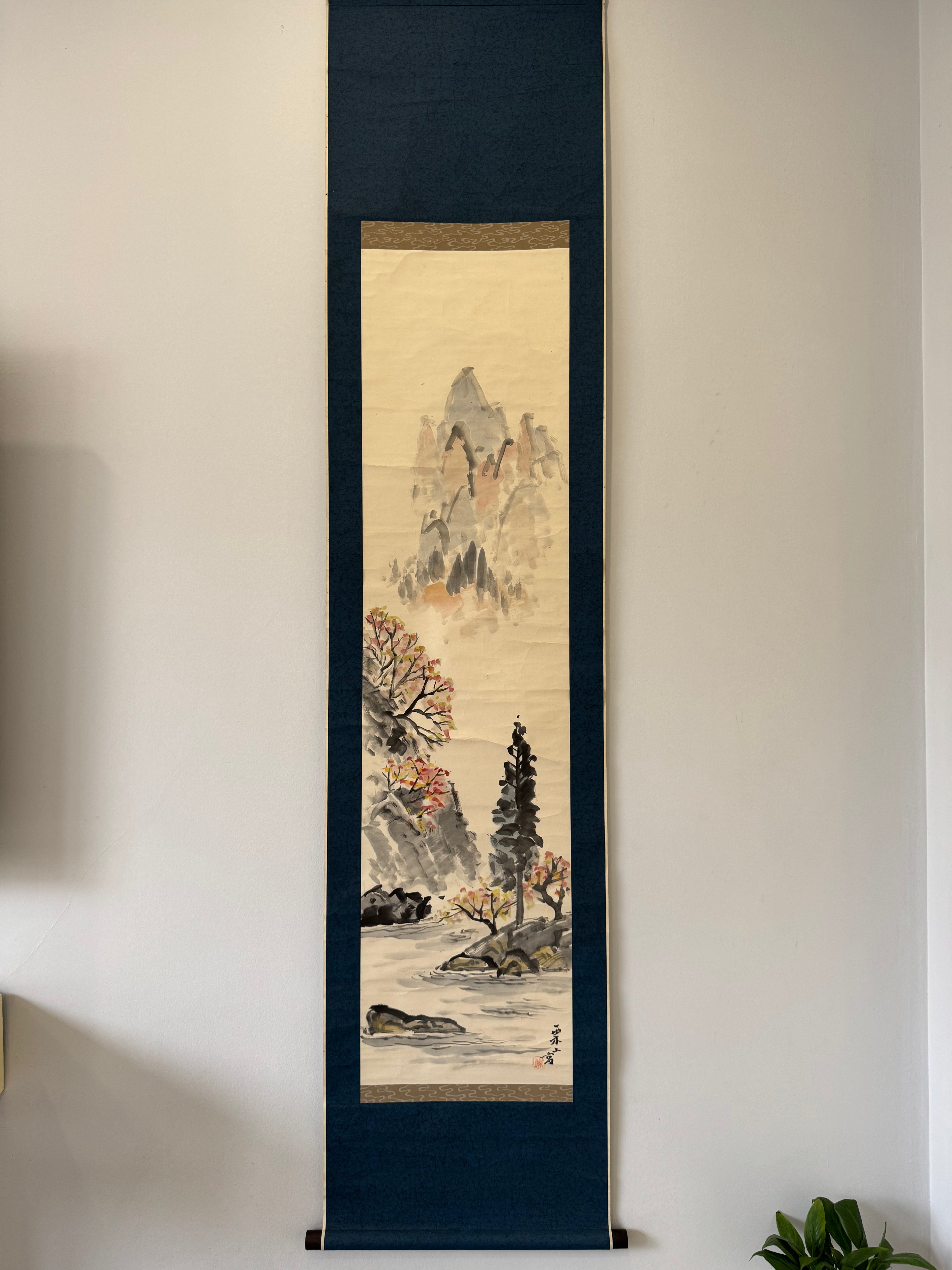 Vertical traditional artwork in a dark wooden frame on a light wall.